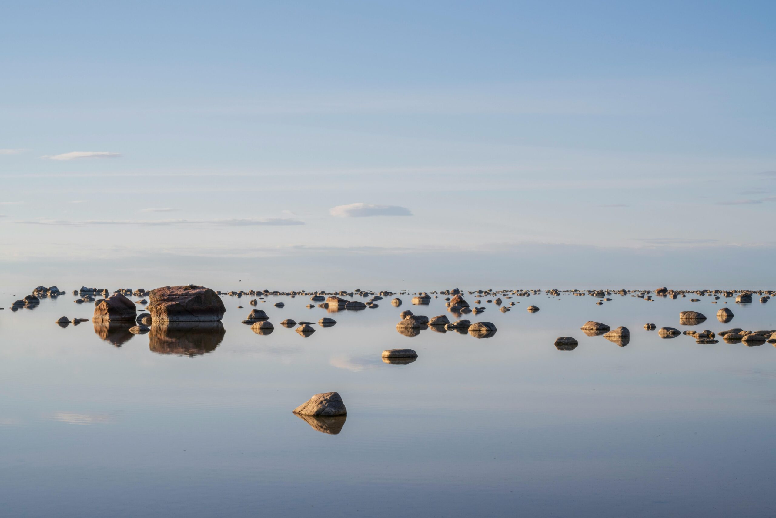 Tranquil view of rocks reflecting on calm waters of the Baltic Sea in Estonia during day.